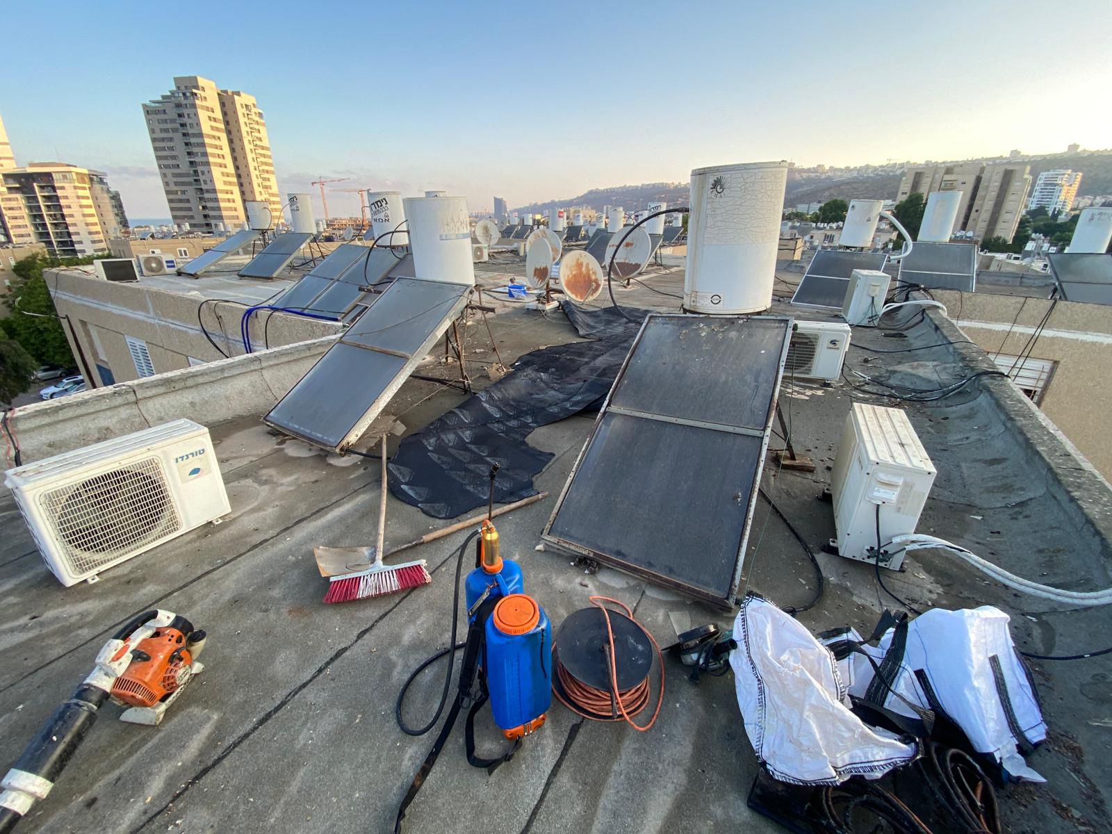 איטום גגות בטירת הכרמל – גג ישן עם קולטי שמש ודודי מים לפני עבודות איטום