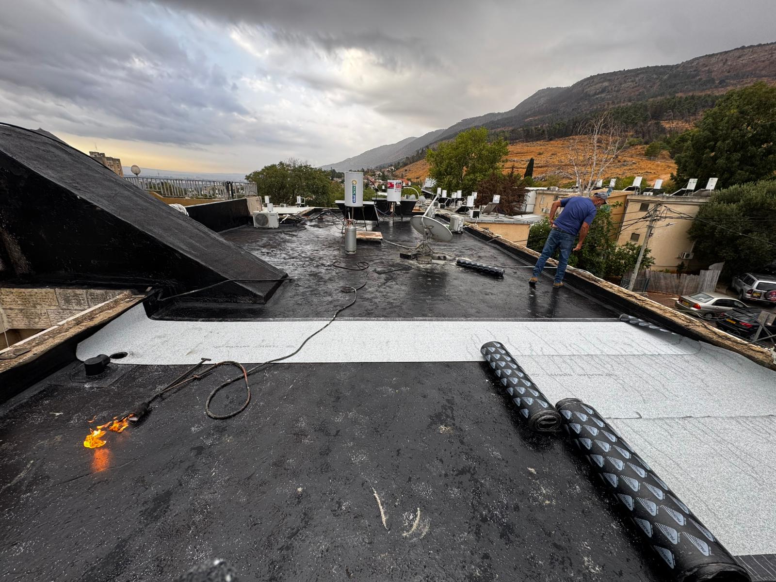 איטום גג ביריעות ביטומניות בקריית שמונה – פריסת יריעות על גג גדול בתחילת העבודה