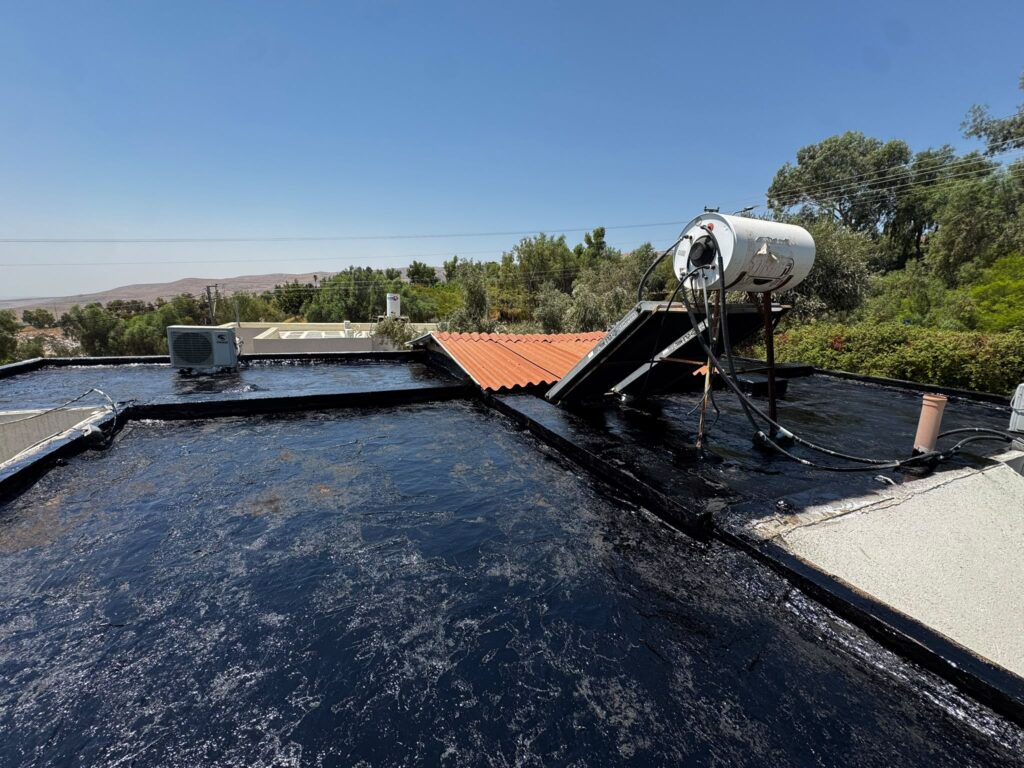 איטום גגות במעלה אפריים: קילוף האיטום הישן והנחת יריעות ביטומניות 2 איטום בשכבת ביטומן סביב דוד השמש והקולטים בגג הבית במעלה אפריים