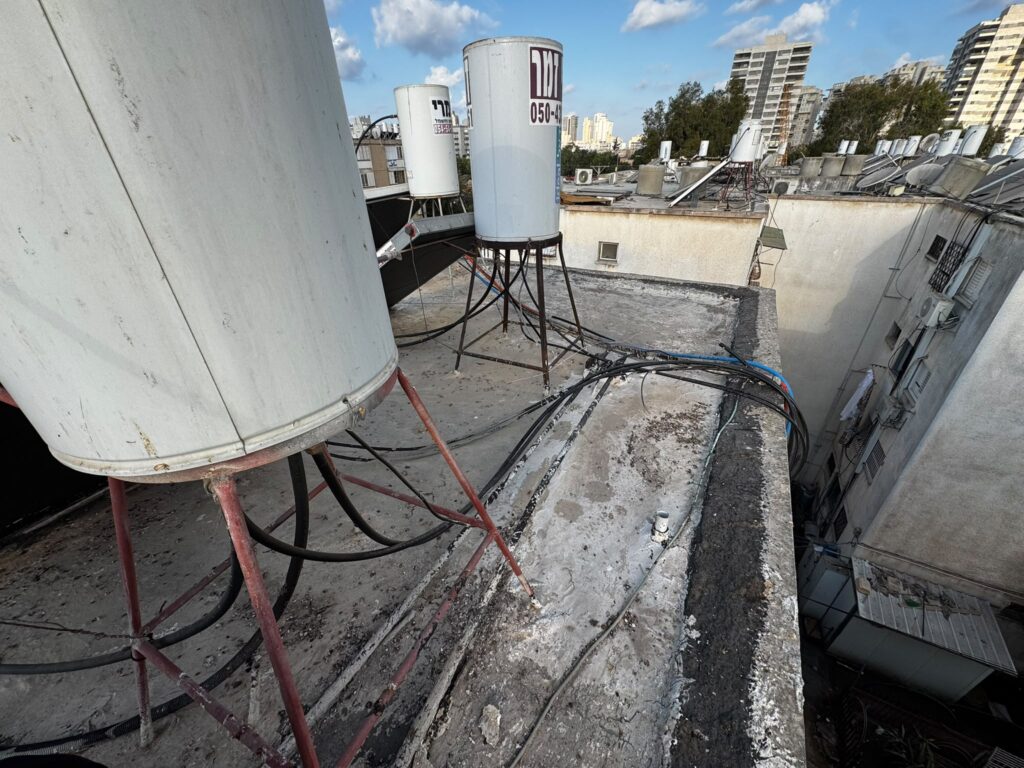 איטום גג בבניין משותף בנתניה: הרמת דודי שמש ואיטום מלא ברחוב הנביאים 5 1 גג בניין משותף בנתניה לפני איטום: דודי שמש, קולטים ואיטום ישן וסדוק ברחוב הנביאים 5